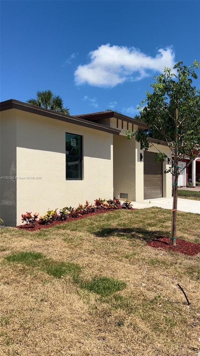 1240 NW 30th Ave, Fort Lauderdale, FL 33311 - view of side of property with a garage, stucco siding, a yard, and driveway
