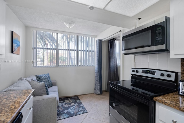 100 Golden Isles Dr Unit 101, Hallandale Beach, FL 33009 - kitchen featuring appliances with stainless steel finishes, white cabinets, a textured ceiling, backsplash, and light tile patterned flooring