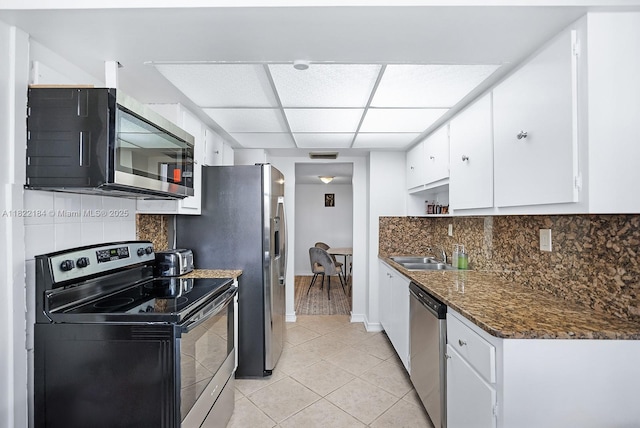 100 Golden Isles Dr Unit 101, Hallandale Beach, FL 33009 - kitchen featuring appliances with stainless steel finishes, decorative backsplash, light tile patterned floors, white cabinets, and a paneled ceiling