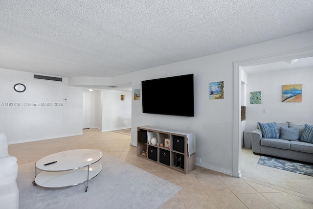 100 Golden Isles Dr Unit 101, Hallandale Beach, FL 33009 - tiled living area featuring a textured ceiling and baseboards