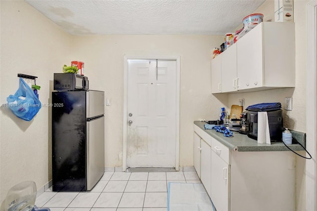 7950 NW 174th Ter, Hialeah, FL 33015 - kitchen featuring freestanding refrigerator, black microwave, white cabinetry, a textured ceiling, and light tile patterned flooring