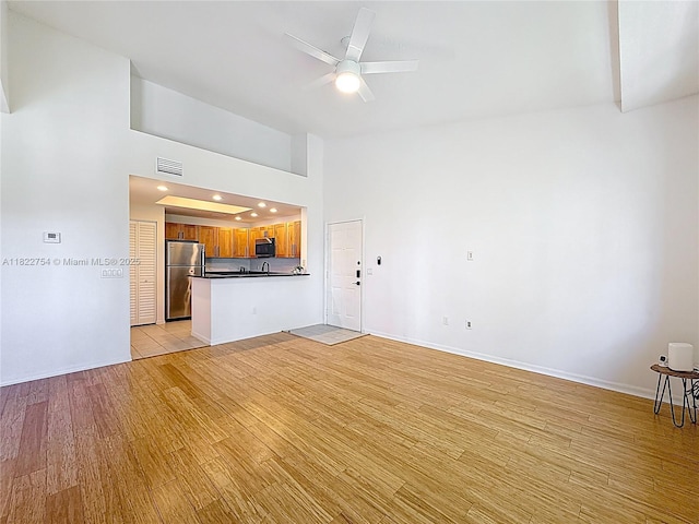 2015 SE 10th Ave Unit 123, Fort Lauderdale, FL 33316 - unfurnished living room with light wood-type flooring, ceiling fan, and a high ceiling