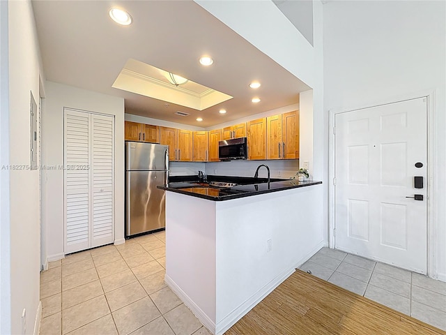 2015 SE 10th Ave Unit 123, Fort Lauderdale, FL 33316 - kitchen featuring appliances with stainless steel finishes, dark countertops, light tile patterned floors, a peninsula, and a raised ceiling
