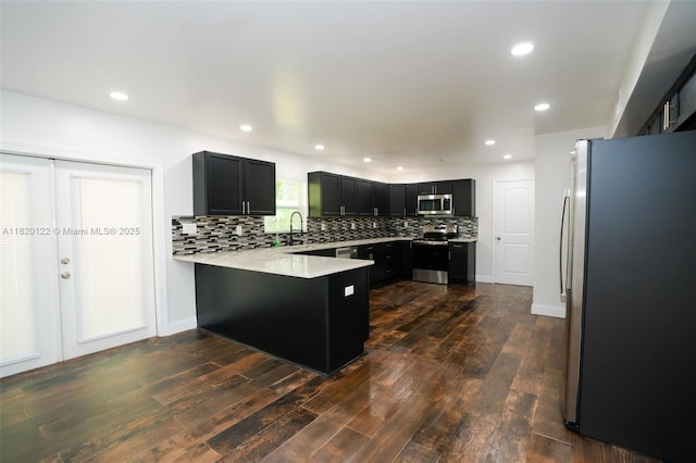 3313 N Ridge Rd, Tallahassee, FL 32305 - kitchen with stainless steel appliances, a peninsula, tasteful backsplash, dark cabinetry, and dark wood-style floors