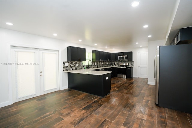 3313 N Ridge Rd, Tallahassee, FL 32305 - kitchen with stainless steel appliances, a peninsula, dark cabinets, decorative backsplash, and light countertops