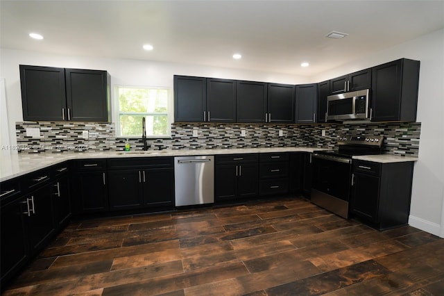 3313 N Ridge Rd, Tallahassee, FL 32305 - kitchen with appliances with stainless steel finishes, dark cabinets, dark wood-style flooring, backsplash, and recessed lighting