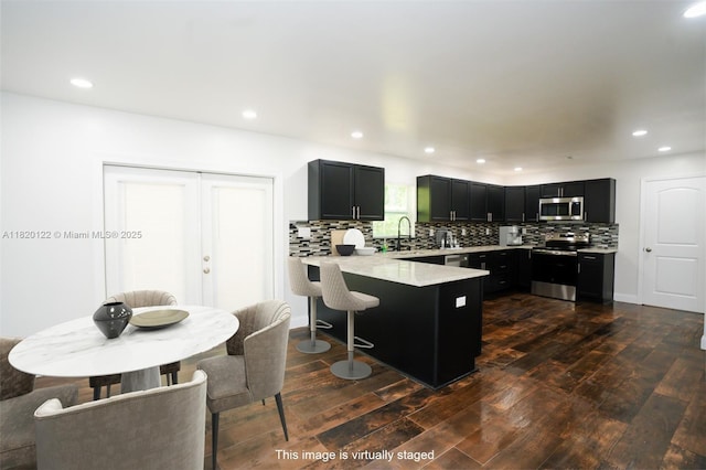 3313 N Ridge Rd, Tallahassee, FL 32305 - kitchen with stainless steel appliances, a peninsula, dark wood-style flooring, dark cabinetry, and recessed lighting