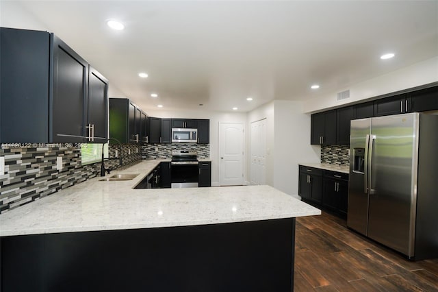 3313 N Ridge Rd, Tallahassee, FL 32305 - kitchen featuring stainless steel appliances, backsplash, light stone countertops, dark wood-style floors, and a peninsula
