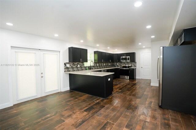 3313 N Ridge Rd, Tallahassee, FL 32305 - kitchen featuring stainless steel appliances, a peninsula, dark cabinetry, backsplash, and light countertops