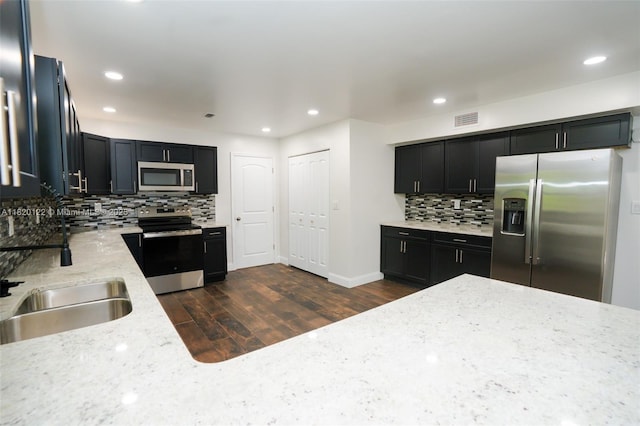 3313 N Ridge Rd, Tallahassee, FL 32305 - kitchen with stainless steel appliances, decorative backsplash, dark cabinets, light stone counters, and recessed lighting