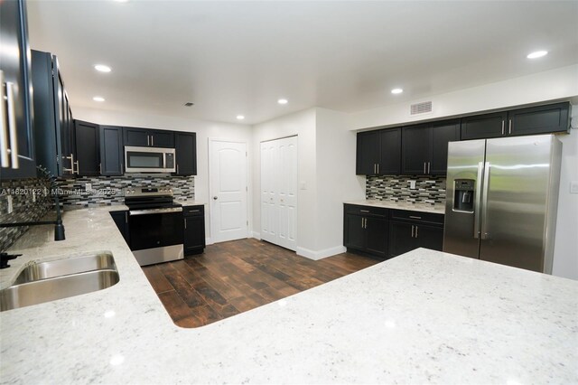 3313 N Ridge Rd, Tallahassee, FL 32305 - kitchen featuring stainless steel appliances, decorative backsplash, dark cabinetry, light stone counters, and recessed lighting