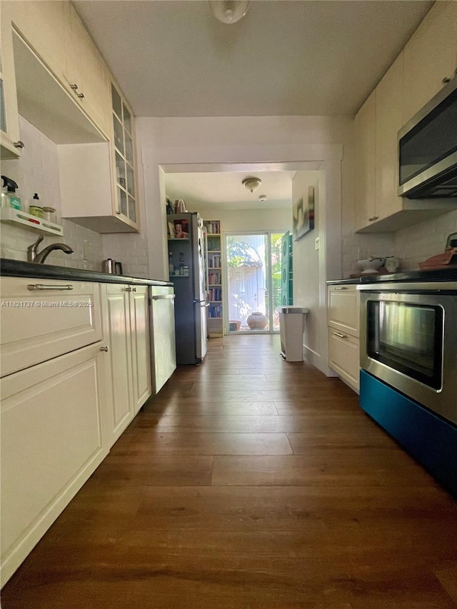 2985 Aviation Ave, Miami, FL 33133 - kitchen with appliances with stainless steel finishes, dark wood-style floors, glass insert cabinets, dark countertops, and white cabinets