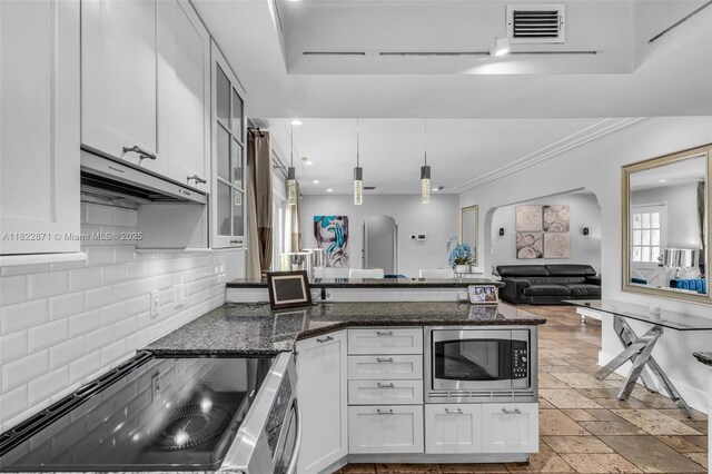 170 NW 105th St, Miami Shores, FL 33150 - kitchen featuring stainless steel microwave, range, backsplash, a peninsula, and white cabinets