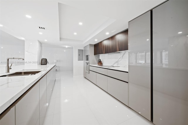 10205 Collins Ave Unit 1504, Bal Harbour, FL 33154 - kitchen featuring modern cabinets, light stone countertops, recessed lighting, a raised ceiling, and light tile patterned floors