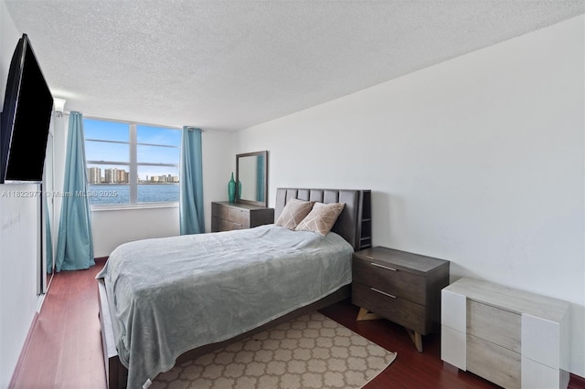251 174th St Unit 218, Sunny Isles Beach, FL 33160 - bedroom featuring dark wood-style floors, a textured ceiling, and a water view