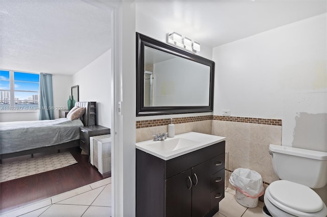 251 174th St Unit 218, Sunny Isles Beach, FL 33160 - bathroom featuring vanity, tile patterned flooring, ensuite bath, tile walls, and wainscoting
