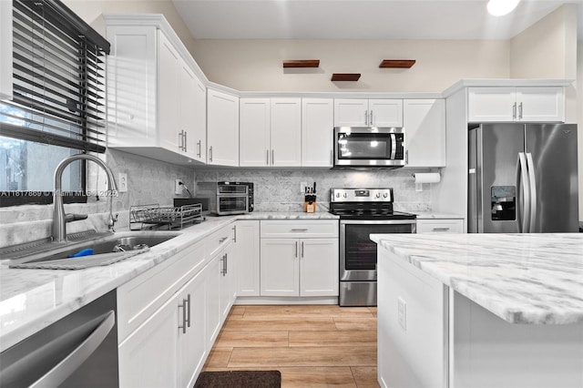 9265 NW 16th St, Pembroke Pines, FL 33024 - kitchen featuring appliances with stainless steel finishes, white cabinetry, backsplash, light wood-style floors, and light stone counters