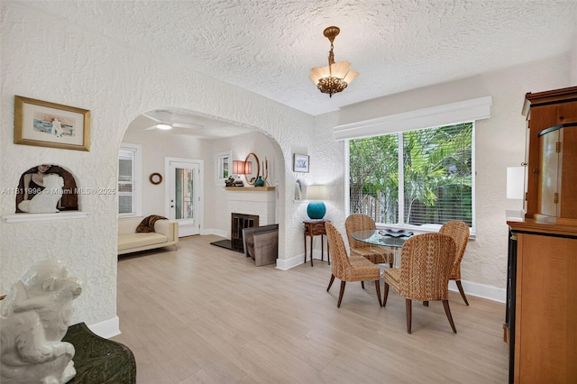 1314 SE 1st Ave, Fort Lauderdale, FL 33316 - dining space featuring arched walkways, a textured wall, a fireplace, a textured ceiling, and light wood-style flooring