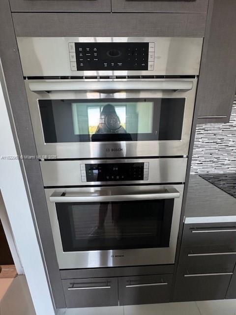 7875 NW 107th Ave Unit 410, Doral, FL 33178 - kitchen view of stainless steel double oven, mail area, and tasteful backsplash