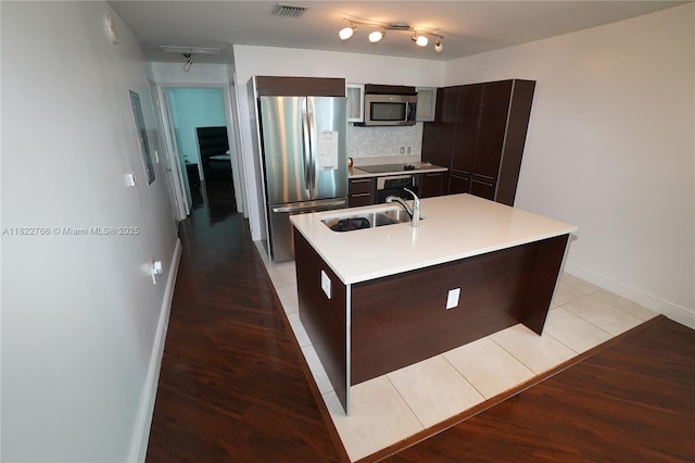 1900 N Bayshore Dr Unit 2510, Miami, FL 33132 - kitchen with appliances with stainless steel finishes, dark brown cabinetry, light countertops, a kitchen island with sink, and decorative backsplash