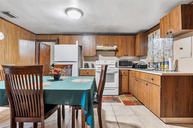 2390 Service Rd, Opa-Locka, FL 33054 - kitchen featuring white appliances, under cabinet range hood, light countertops, brown cabinets, and light tile patterned floors
