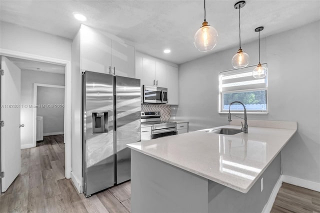 4622 SW 23rd St, West Park, FL 33023 - kitchen with appliances with stainless steel finishes, white cabinets, a peninsula, hanging light fixtures, and light wood-type flooring