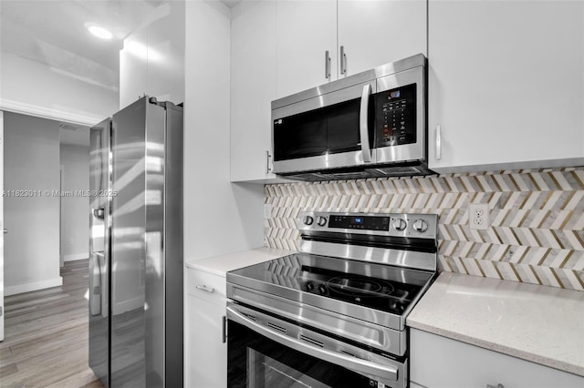 4622 SW 23rd St, West Park, FL 33023 - kitchen with stainless steel appliances, white cabinetry, decorative backsplash, light stone countertops, and light wood-type flooring