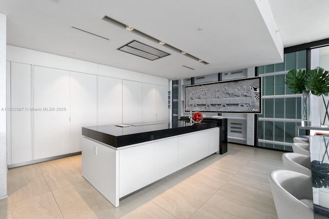 1000 Biscayne Blvd Unit 3402, Miami, FL 33132 - kitchen with light tile patterned flooring, white cabinetry, dark countertops, and a kitchen island