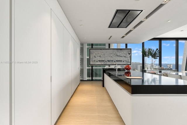 1000 Biscayne Blvd Unit 3402, Miami, FL 33132 - kitchen featuring modern cabinets, white cabinets, dark countertops, light wood-type flooring, and a large island