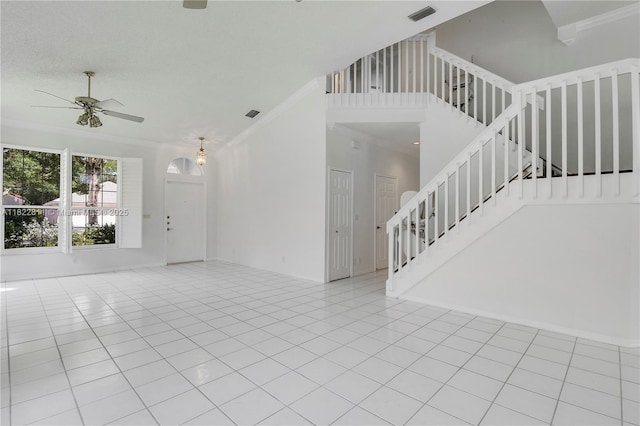 2278 SW Olympic Club Ter, Palm City, FL 34990 - unfurnished living room with crown molding, ceiling fan, stairs, a towering ceiling, and tile patterned flooring