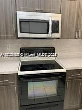 3100 W Rolling Hills Cir Unit 101, Davie, FL 33328 - kitchen with black range with electric stovetop, stainless steel microwave, light countertops, and dark brown cabinets