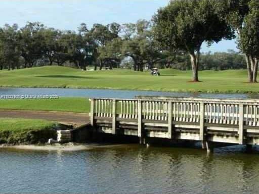 3100 W Rolling Hills Cir Unit 101, Davie, FL 33328 - dock with a water view, a yard, golf course view, and view of wooded area