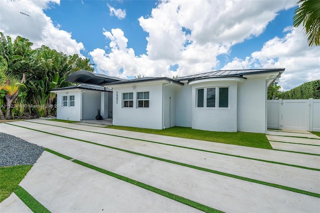 1331 97th St, Bay Harbor Islands, FL 33154 - rear view of house featuring stucco siding, a standing seam roof, a gate, a metal roof, and driveway
