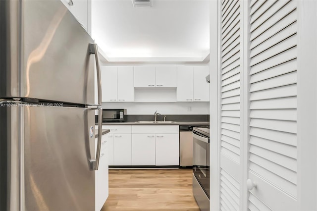 8335 SW 72nd Ave Unit 315D, Miami, FL 33143 - kitchen featuring appliances with stainless steel finishes, white cabinets, dark countertops, light wood finished floors, and open shelves