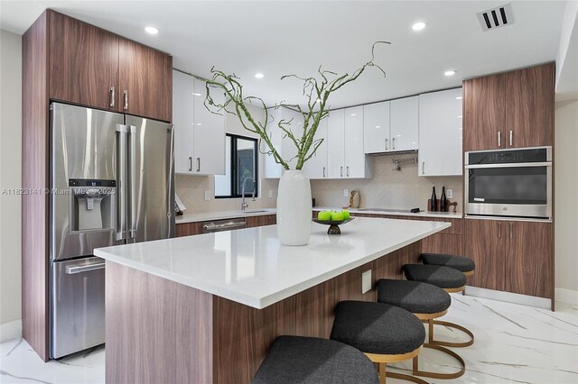 4300 Monroe St, Hollywood, FL 33021 - kitchen featuring appliances with stainless steel finishes, light marble finish flooring, tasteful backsplash, a kitchen bar, and recessed lighting