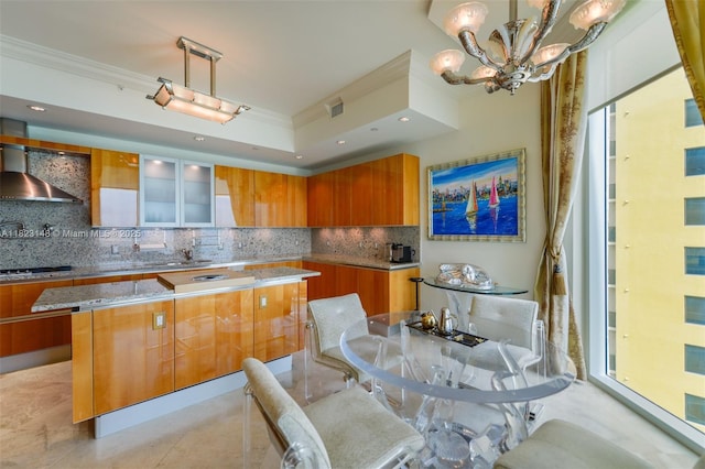 16051 Collins Ave Unit 1104, Sunny Isles Beach, FL 33160 - kitchen with wall chimney range hood, crown molding, brown cabinetry, a chandelier, and modern cabinets