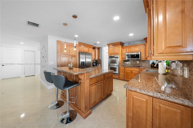 2631 SW 180th Ave, Miramar, FL 33029 - kitchen with stainless steel appliances, backsplash, a breakfast bar, stone countertops, and recessed lighting