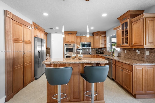 2631 SW 180th Ave, Miramar, FL 33029 - kitchen with stainless steel appliances, a kitchen island, recessed lighting, light stone countertops, and a breakfast bar area