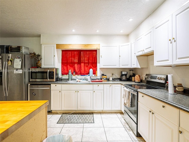 907 S Amelia Ave, Deltona, FL 32724 - kitchen with appliances with stainless steel finishes, a textured ceiling, white cabinets, light tile patterned flooring, and recessed lighting