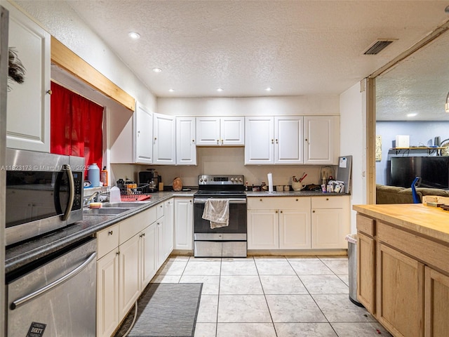 907 S Amelia Ave, Deltona, FL 32724 - kitchen with appliances with stainless steel finishes, a textured ceiling, light tile patterned floors, white cabinets, and recessed lighting