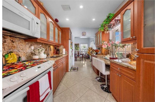 611 E 48th St, Hialeah, FL 33013 - kitchen with white appliances, backsplash, glass insert cabinets, brown cabinetry, and recessed lighting