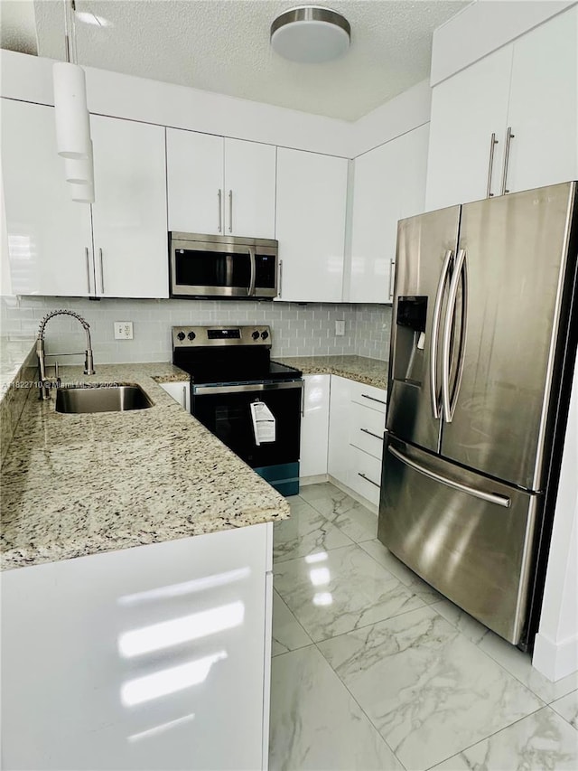 18961 NW 22nd St, Pembroke Pines, FL 33029 - kitchen with appliances with stainless steel finishes, light marble finish floors, white cabinetry, tasteful backsplash, and light stone countertops