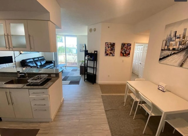 275 NE 18th St Unit 402, Miami, FL 33132 - kitchen featuring white cabinets, light wood finished floors, dark countertops, and glass insert cabinets