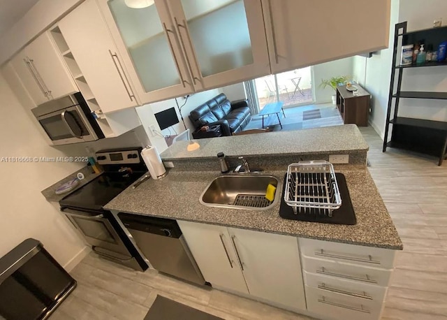 275 NE 18th St Unit 402, Miami, FL 33132 - kitchen with appliances with stainless steel finishes, light wood-type flooring, white cabinets, glass insert cabinets, and dark stone counters