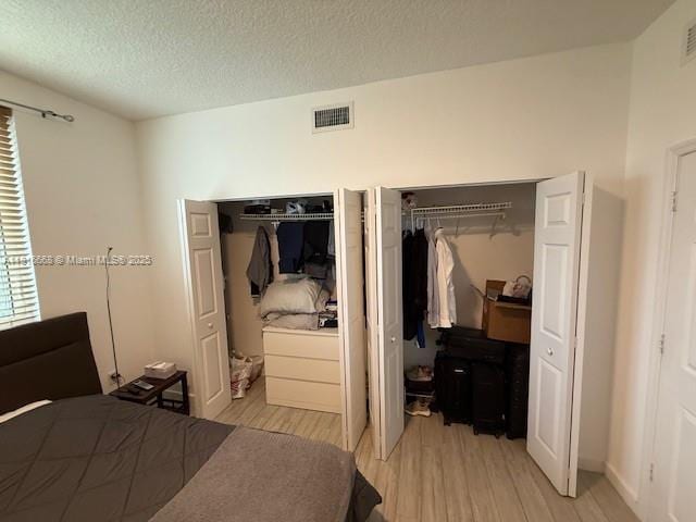 275 NE 18th St Unit 402, Miami, FL 33132 - bedroom with multiple closets, light wood finished floors, and a textured ceiling