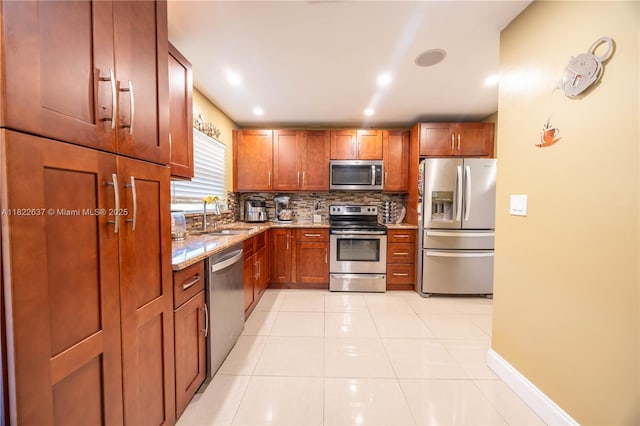 11351 NW 37th St, Coral Springs, FL 33065 - kitchen with appliances with stainless steel finishes, backsplash, light stone countertops, light tile patterned floors, and brown cabinetry