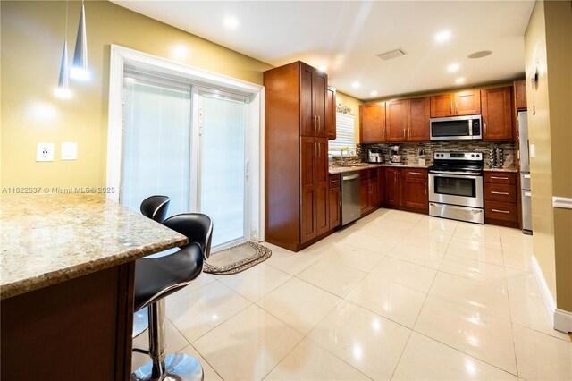 11351 NW 37th St, Coral Springs, FL 33065 - kitchen with stainless steel appliances, tasteful backsplash, a kitchen bar, light stone counters, and recessed lighting