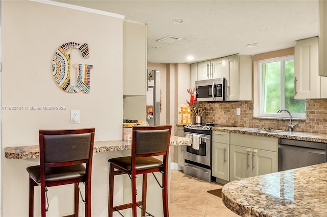 6797 SW 40th St Unit 71, Davie, FL 33314 - kitchen with appliances with stainless steel finishes, decorative backsplash, a kitchen breakfast bar, light stone countertops, and recessed lighting