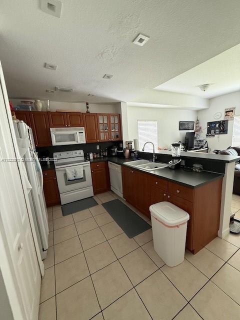 8960 W Flagler St Unit 1, Miami, FL 33174 - kitchen featuring white appliances, dark countertops, light tile patterned floors, and a peninsula