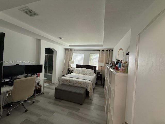 8960 W Flagler St Unit 1, Miami, FL 33174 - bedroom with arched walkways, a desk, light wood-style floors, and a tray ceiling